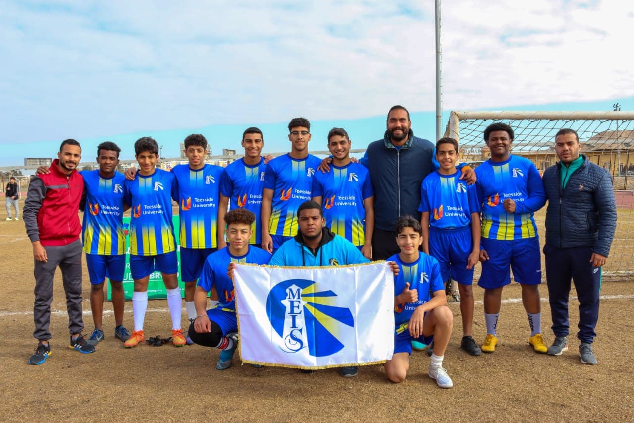 The MEIS football team with the school flag